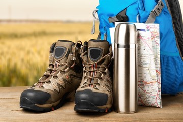 Hiking boots, backpack and map  on background