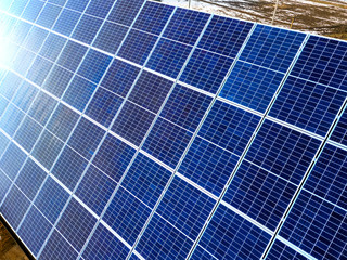 Close-up surface of lit by sun blue shiny solar photo voltaic panels system on building roof....