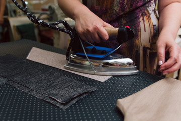 A woman strokes the fabric for further sewing. Tailor ironing clothes