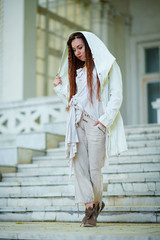 dreadlocks fashionable girl dressed in white posing on old palace background