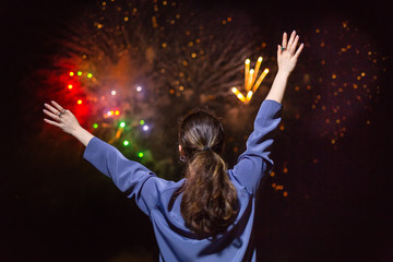 A young brunette woman enjoys the fireworks in the sky.Concept of festivals and holidays with fireworks. The view from the back