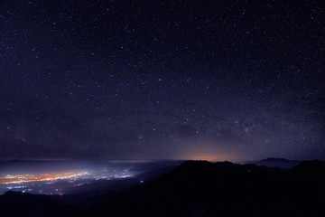 Fototapeta na wymiar Mountain view morning at night of top hills and city around with soft fog under the stars in dark sky background, Monzone View Point Doi Ang Khang, Chiang Mai, northern of Thailand.