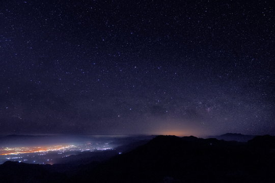 Mountain view morning at night of top hills and city around with soft fog under the stars in dark sky background, Monzone View Point Doi Ang Khang, Chiang Mai, northern of Thailand.
