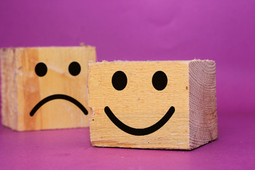 smiley face and blurred sad face icon on big wood cube, Service rating, satisfaction concept
