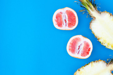 Bright flat lay on a blue background with pineapples and grapefruit.