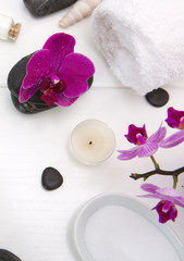 Spa setting with pink orchids, black stones and bath salts on white wood .