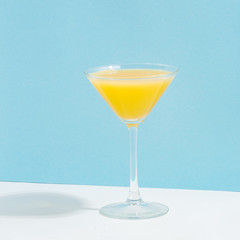 Fruit berry drink in a glass with ice on a colored background.