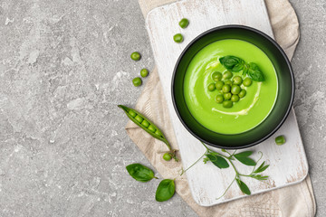 Soup of young green peas with basil leaves on gray