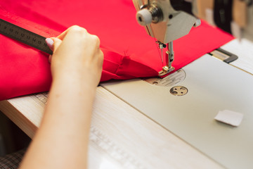 Tailor measures fabric with a ruler. Woman works in a garment factory