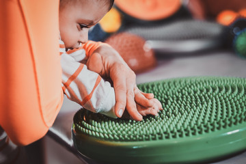 Little pretty baby is curious about special treatment toy at masseur cabinet.