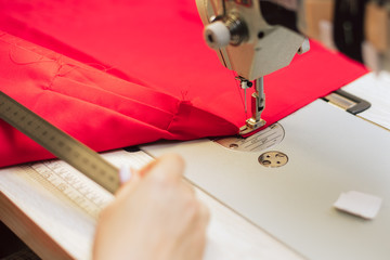 Tailor measures fabric with a ruler. Woman works in a garment factory