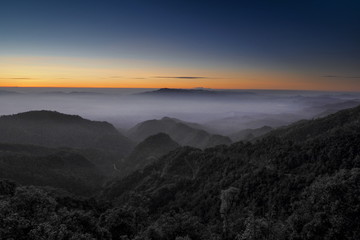 Mountain view misty morning of top hills around with sea of fog with red and yellow sun light in the sky background, sunrise at Doi Ang Khang, Monzone view point, Chiang Mai, Thailand.