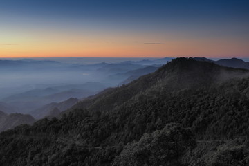 Mountain view misty morning of top hills around with sea of fog with red and yellow sun light in the sky background, sunrise at Doi Ang Khang, Monzone view point, Chiang Mai, Thailand.