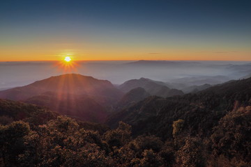 Obraz premium Mountain view misty morning of top hills around with sea of fog with red and yellow sun light in the sky background, sunrise at Doi Ang Khang, Monzone view point, Chiang Mai, Thailand.