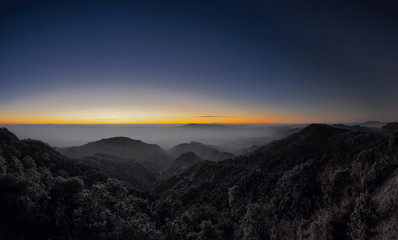 Mountain view misty morning of top hills around with sea of fog with red and yellow sun light in the sky background, sunrise at Doi Ang Khang, Monzone view point, Chiang Mai, Thailand.