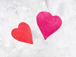two different hearts cut from papers on gray
