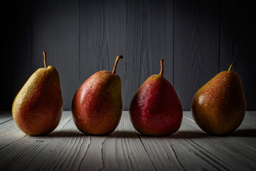 FOUR PEARS ON THE WHITE WOODEN COUNTER TOP GRAY WOODEN REAR BACKGROUND