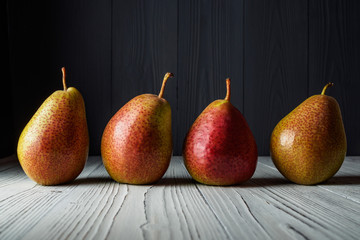 FOUR PEARS ON THE WHITE WOODEN COUNTER TOP GRAY WOODEN REAR BACKGROUND