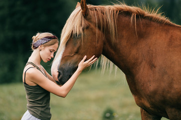 Young beautiful girl hugging horse at nature. Horse lover.