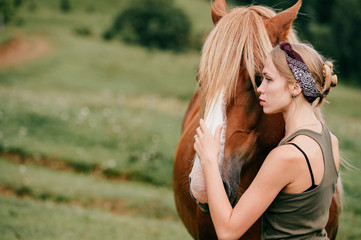 Young beautiful girl hugging horse at nature. Horse lover.