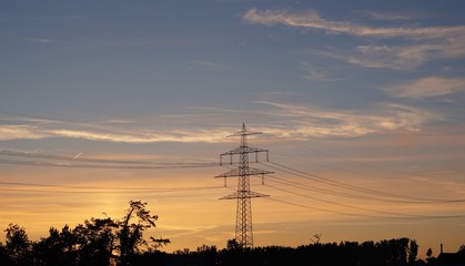 silhouette of a high voltage transmission tower at sunset, electricity pylon, power pole at sundown