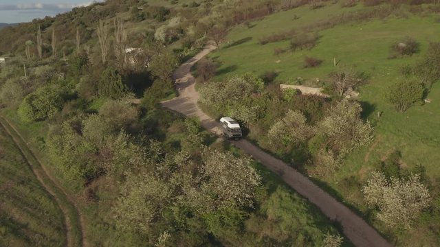 Shooting from air tourist van house on wheels car transporter t3 driving on beautiful tree lined country road. Traveling picturesque country road on hill edge. Tourism blooming. Travel destinations
