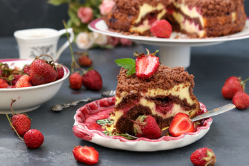 Chocolate cake with cottage cheese with strawberries is located on a dark background, a piece of cake is located in the foreground on a plate
