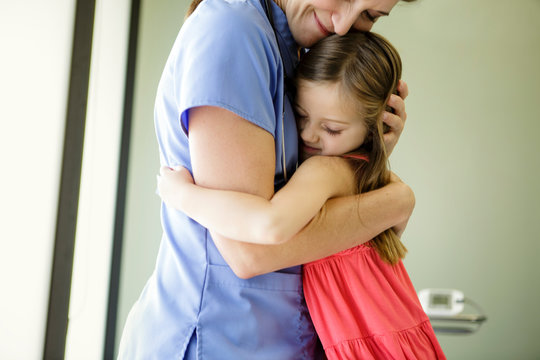 Young girl hugs woman doctor