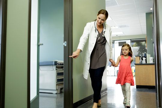 Woman doctor walks young patient to examination room