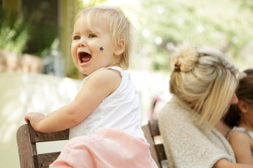 Blonde toddler yelling with sticker on her cheek
