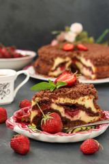 Chocolate cake with cottage cheese with strawberries is located on a dark background, a piece of cake is located in the foreground on a plate