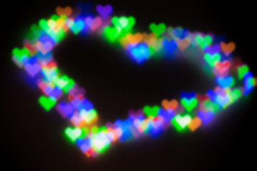 Blurred festive background with defocused colourful glitter formed a heart, bokeh in a shape of a heart. Original photographic effect. Pictures concept theme Love and St. Valentine's Day