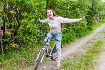Naklejka premium Young woman riding bicycle in summer city park outdoors. Active people. Hipster girl relax and rider bike. Cycling to work at summer day. Bicycle and ecology lifestyle concept