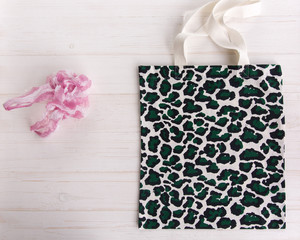 Eco Shopping Bag with trendy leopard pattern print against a plastic bag on white wooden background, Flat Lay. Save planet earth