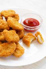Chicken nuggets with ketchup and glass of cold beer on a white wooden background, side view. Close-up.