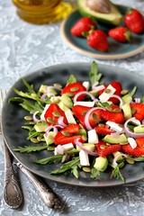 salad with strawberries and avocado, arugula, feta cheese, pumpkin seeds, red onion