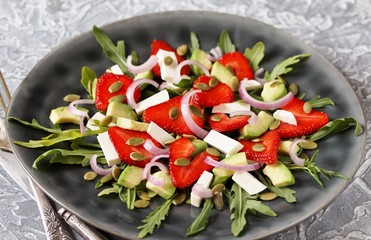 salad with strawberries and avocado, arugula, feta cheese, pumpkin seeds, red onion