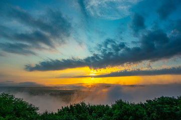 Fototapeta na wymiar Sunrise on a foggy summer morning over the village