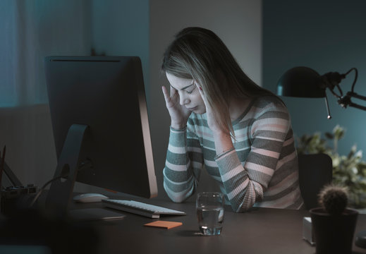 Exhausted woman working at desk late at night