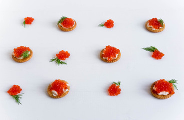 Photo of canape from crackers and red caviar for a buffet table. Red caviar on a white wooden background