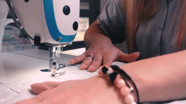 Hands of seamstress using sewing machine