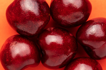 Close up of pile of fresh red shiny cherries on coral background. Texture.