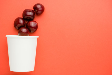 Pile raw cherries above paper cup in the left part of the background.