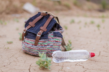Lightweight walking backpack and a bottle of water on the dried ground.