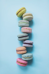 Cake macaron or macaroon on pastel blue background from above. Colorful almond cookies of pastel colors. Top view.