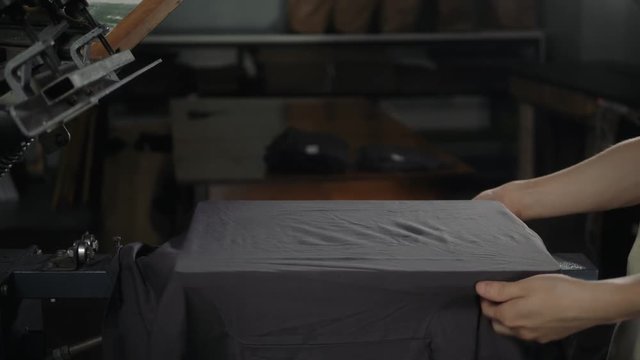 Man close up preparing t-shirt for printing in the silk screen printing machine. Only hands. Man preparing t-shirt for printing in the silk screen printing machine.