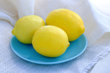 Fresh lemon citrus fruit on blue plate, yellow and blue contrast with food.