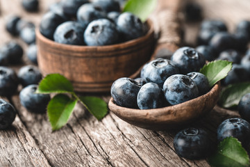 Blueberries in wooden spoon on old wood background. Healthy eating and nutrition concept.