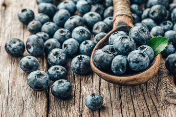 Blueberries in wooden spoon on old wood background. Healthy eating and nutrition concept.