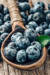 Blueberries in wooden spoon on old wood background. Healthy eating and nutrition concept.